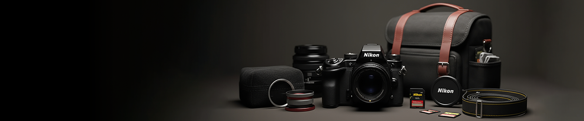 A Nikon camera with lenses, memory cards, a camera bag, lens filters, and camera accessories arranged neatly on a dark surface against a black background.