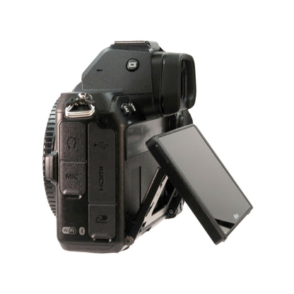 A black Nikon Z 5 Mirrorless Digital Camera with AF-S NIKKOR 28mm f/1.8G Lens and F to Z Adapter Enhanced Macro Kit is shown on a white background, its LCD flipped out and exposing MIC and HDMI ports on the left; it supports 4K video recording.